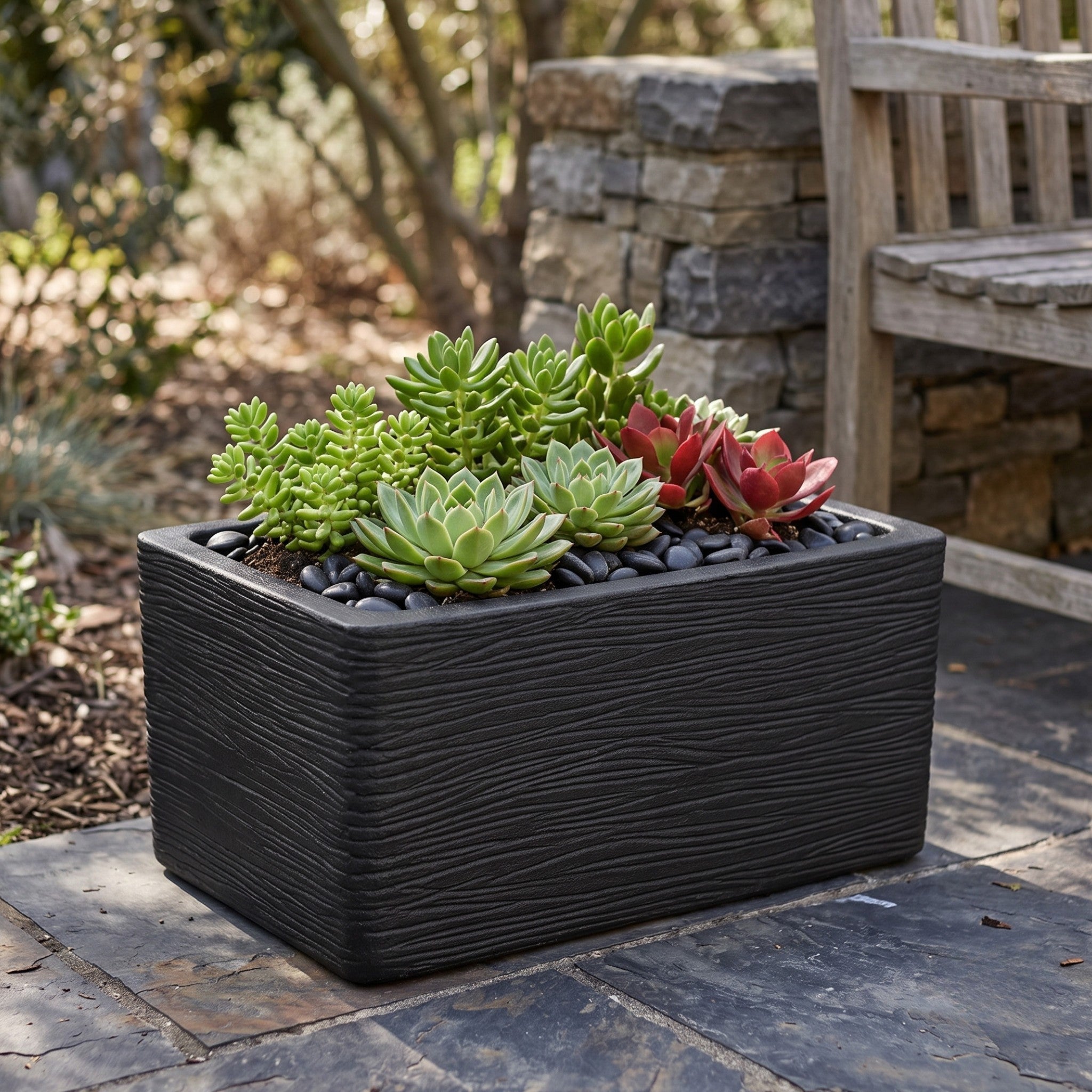 Nora 20-inch black rectangular planter with textured wood-grain finish filled with assorted green and red succulents