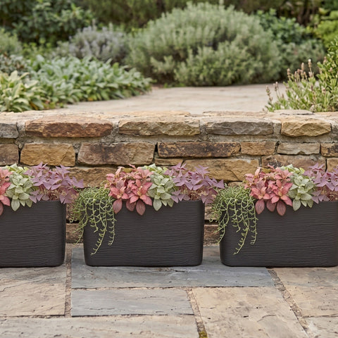 Three Nora Rectangle Series 26 inch planters with textured finish and colorful foliage on a stone patio